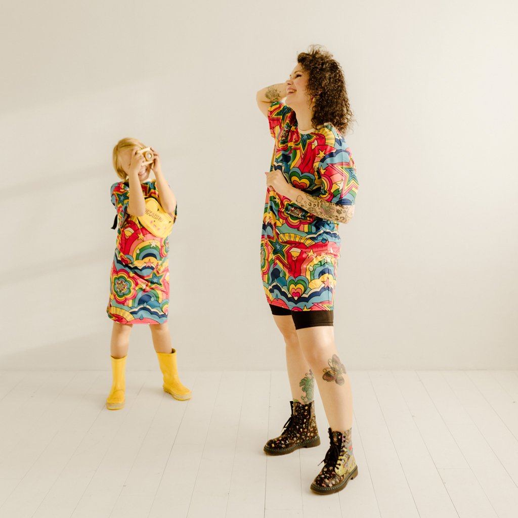 A child taking a picture of a woman in a colorful t-shirt dress by SHALMIAK.
